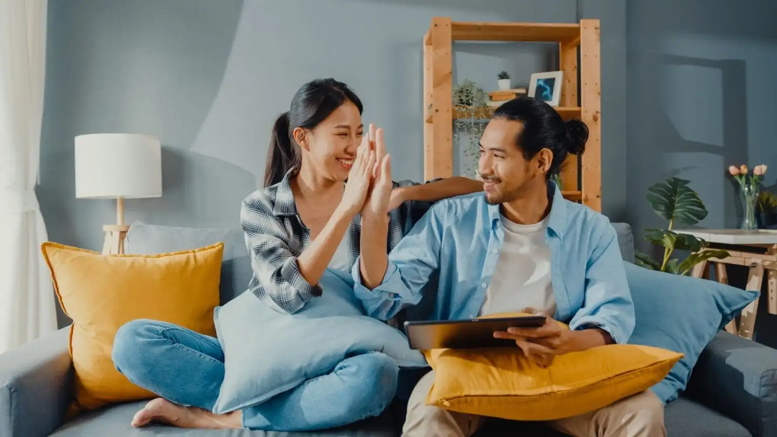 happy-asian-young-attractive-couple-man-woman-sit-couch-use-tablet-shopping-online-furniture-new-house